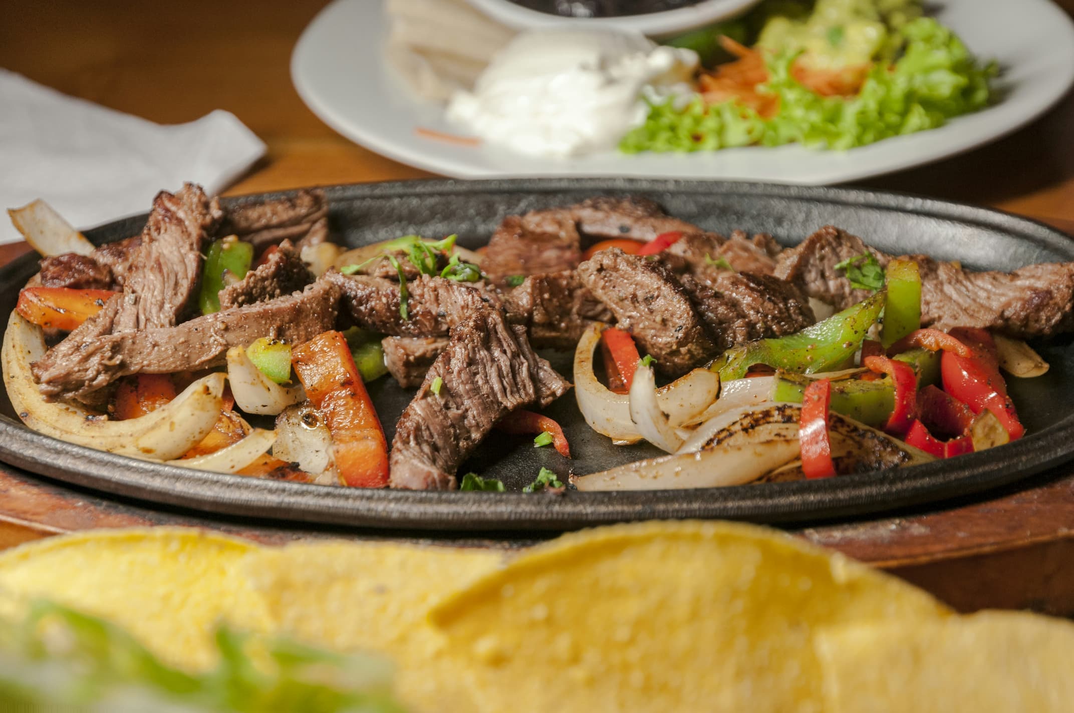 Sizzling steak fajitas on a cast-iron skillet at El Patron